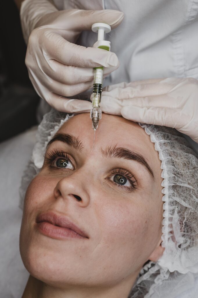 Dentista aplicando um produto com uma agulha na face de uma mulher